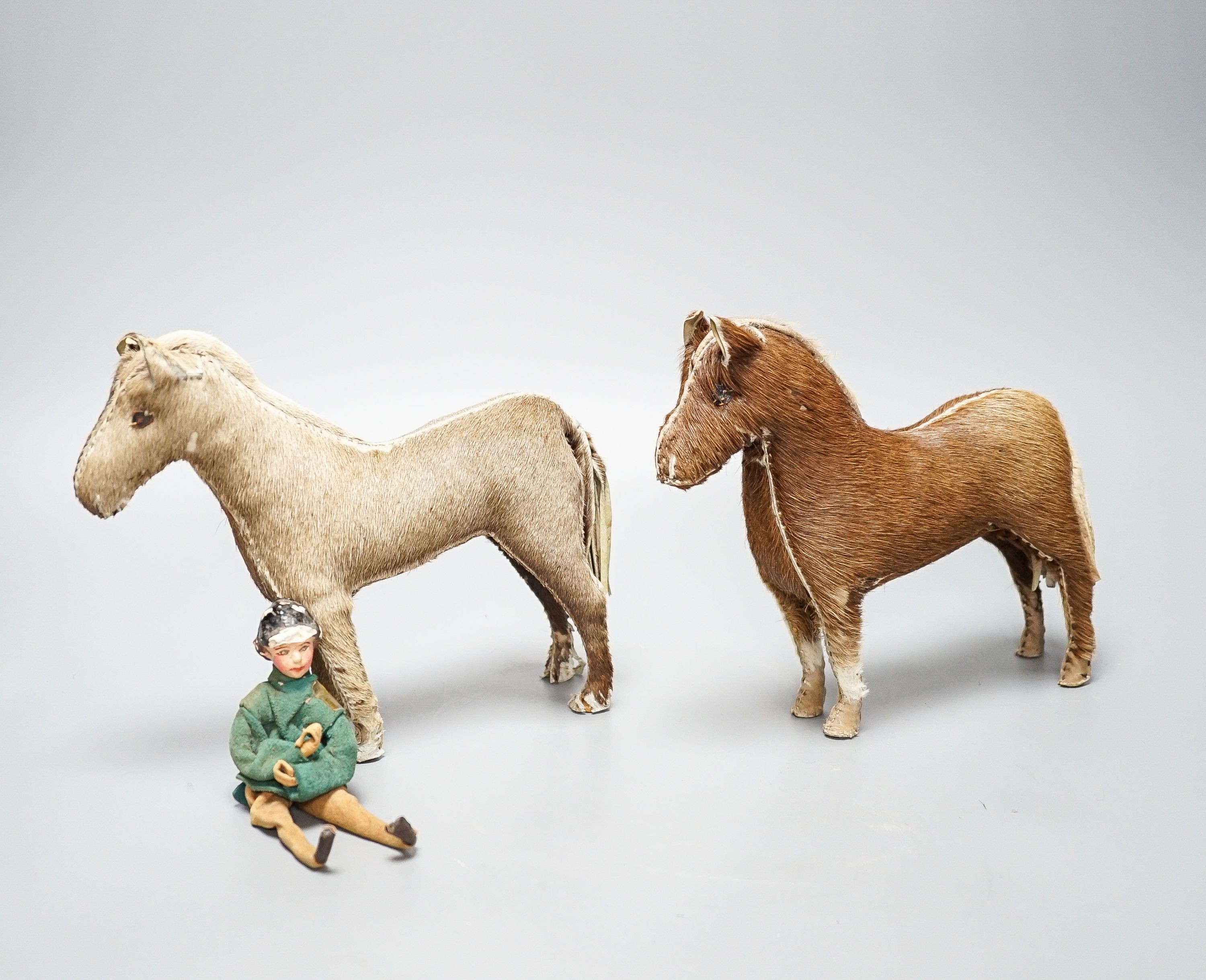 Two Edith Reynolds handmade real skin and leather horse models, 18cm high, together with a female jockey and related leather accessories